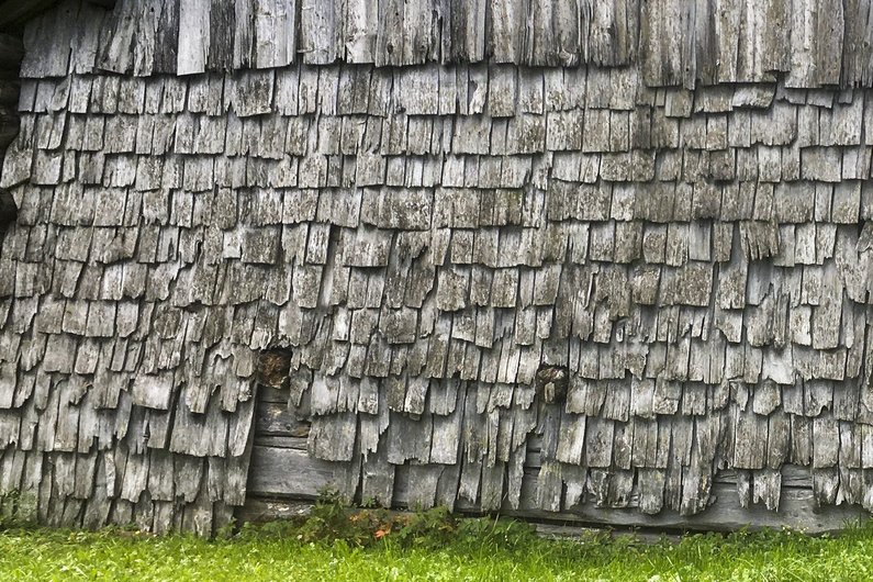 Materialbedingter Abbau einer historischen Brettschindelfassade im Appenzellerland infolge intensiver Sonneneinstrahlung und erhöhter Niederschlagsbelastung.